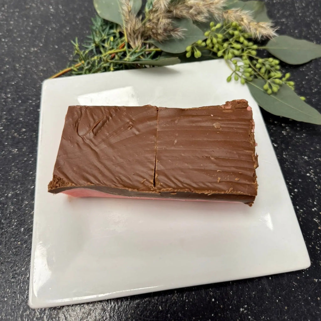 Chocolate bar on a white plate with greenery on a dark surface
